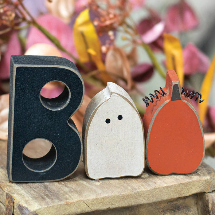 Decorative letters 'B', 'O', and 'O' on a wooden surface with a blurred floral background.